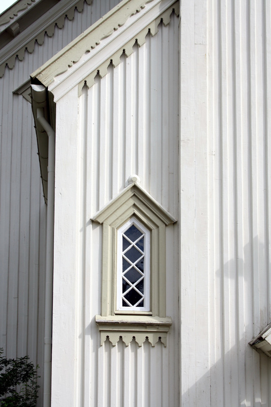 Foto av Saltdal kirke, detalj eksteriør. Hjørne med vindu og dekorarbeid i tre.