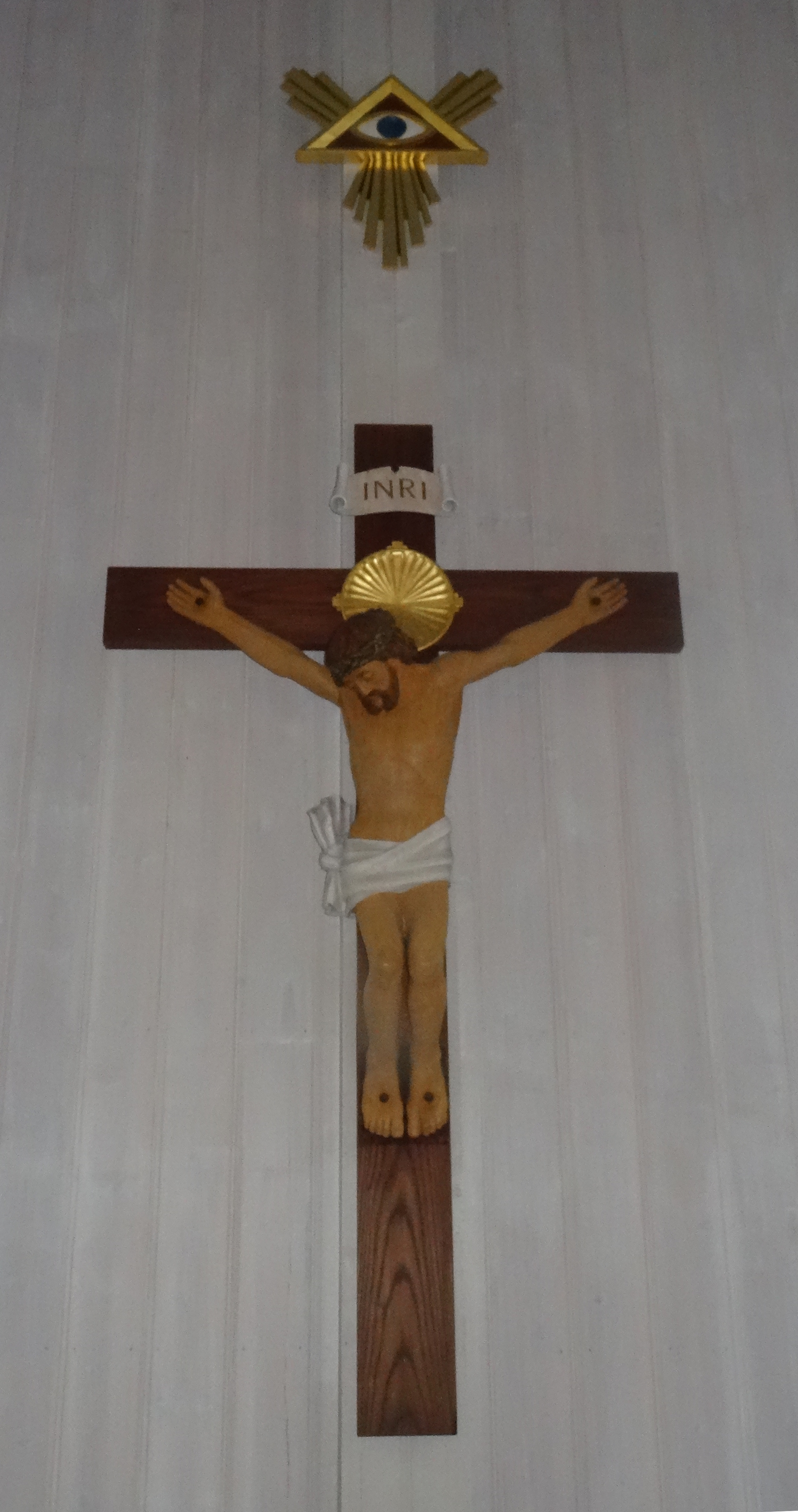 Foto av alterdekorasjonen i Saltdal kirke. Krusifiks i tre med Guds øye over.